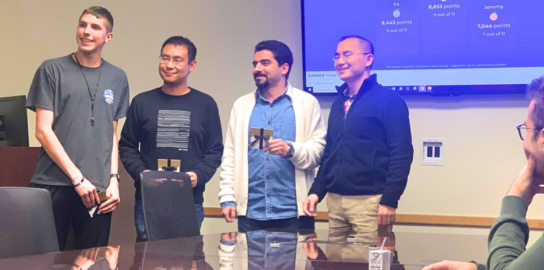 ITE GBM 2019 - A meeting room with a large rectangular table, where a group of four men are standing behind the table and smiling at the camera.