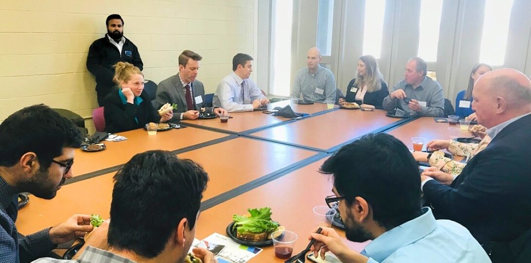 ITE Illinois Student Day 2019 - A meeting room with a large rectangular table, where about 10 people are seated and eating lunch while they talk.