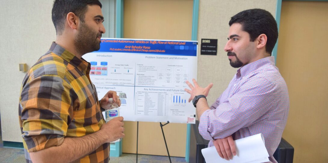 ITE members participating in the CME Poster competition - A man in a checkered flannel shirt and a man in a light purple long-sleeved shirt are standing in front of a research poster on an easel.