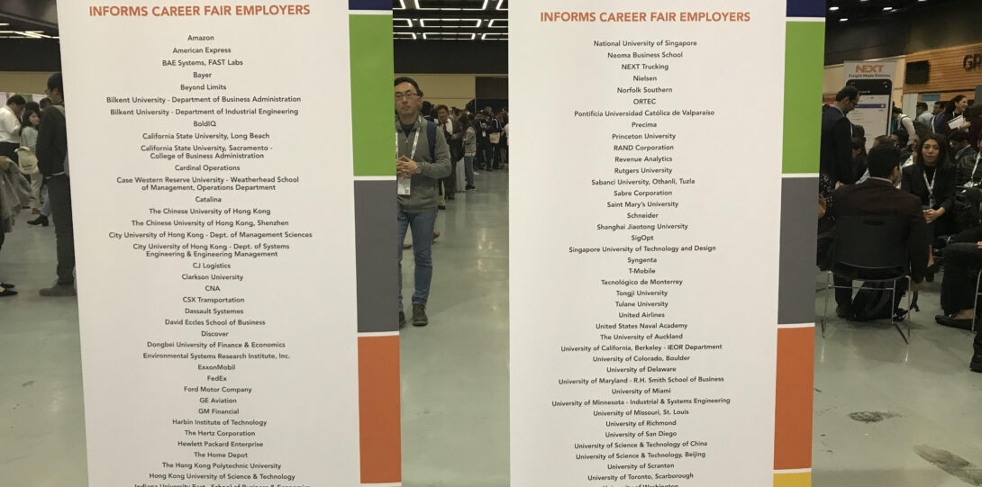 INFORMS 2019 - A career fair hall with two large banners in the foreground.